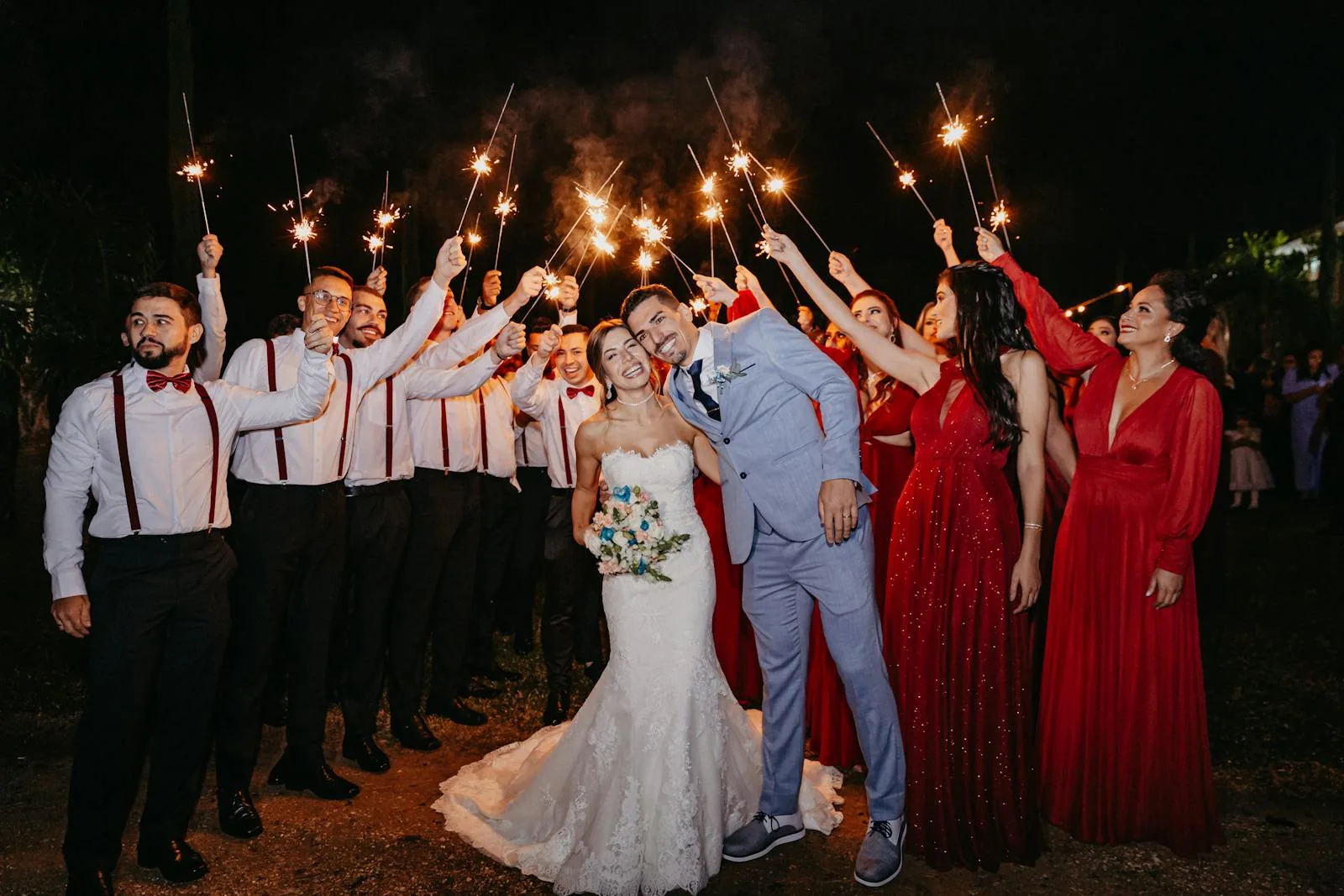 Wedding party celebrating outdoors at night with sparklers