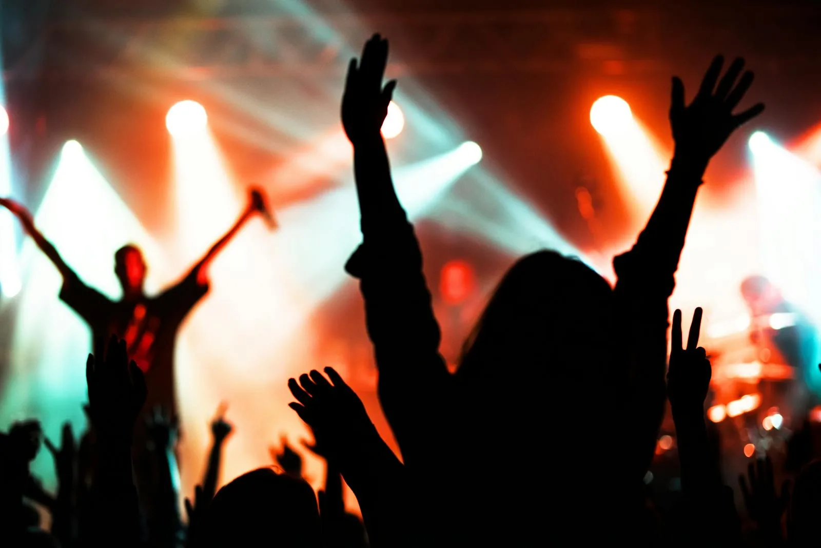 Silhouetted crowd with hands raised at a concert