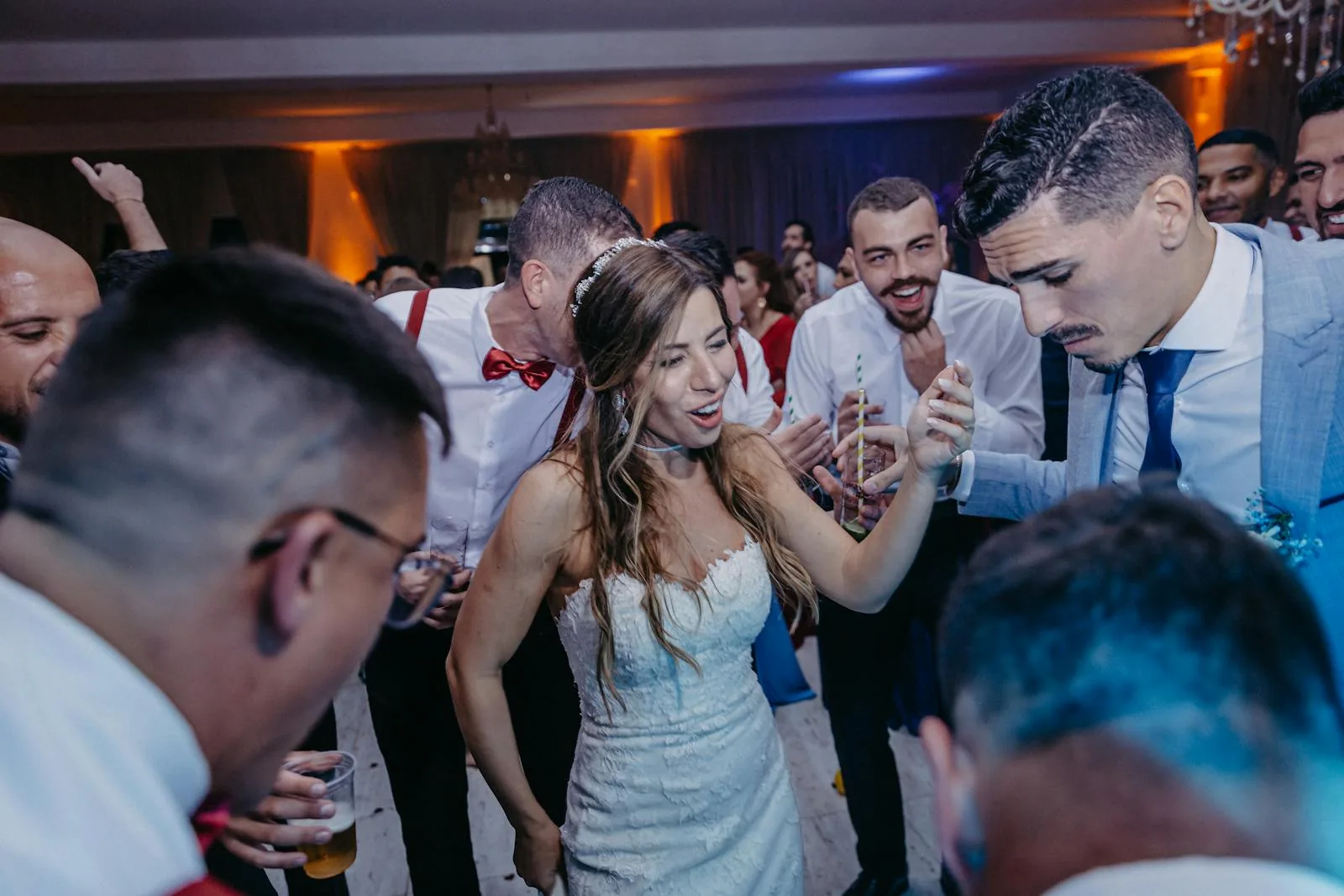Newlyweds dancing with guests at a packed wedding reception
